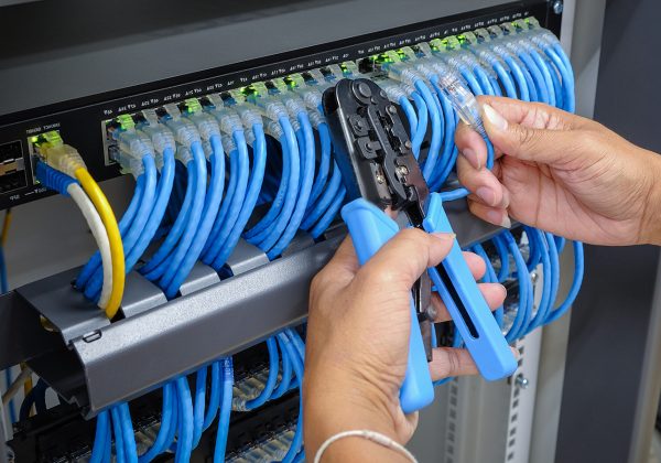 hand of system administrator with network cable connected to patch panel of network gigabit switch and crimping pliers tool; Shutterstock ID 648476824; Job 1: -; Client/Licensee: -; Ordered By: -
